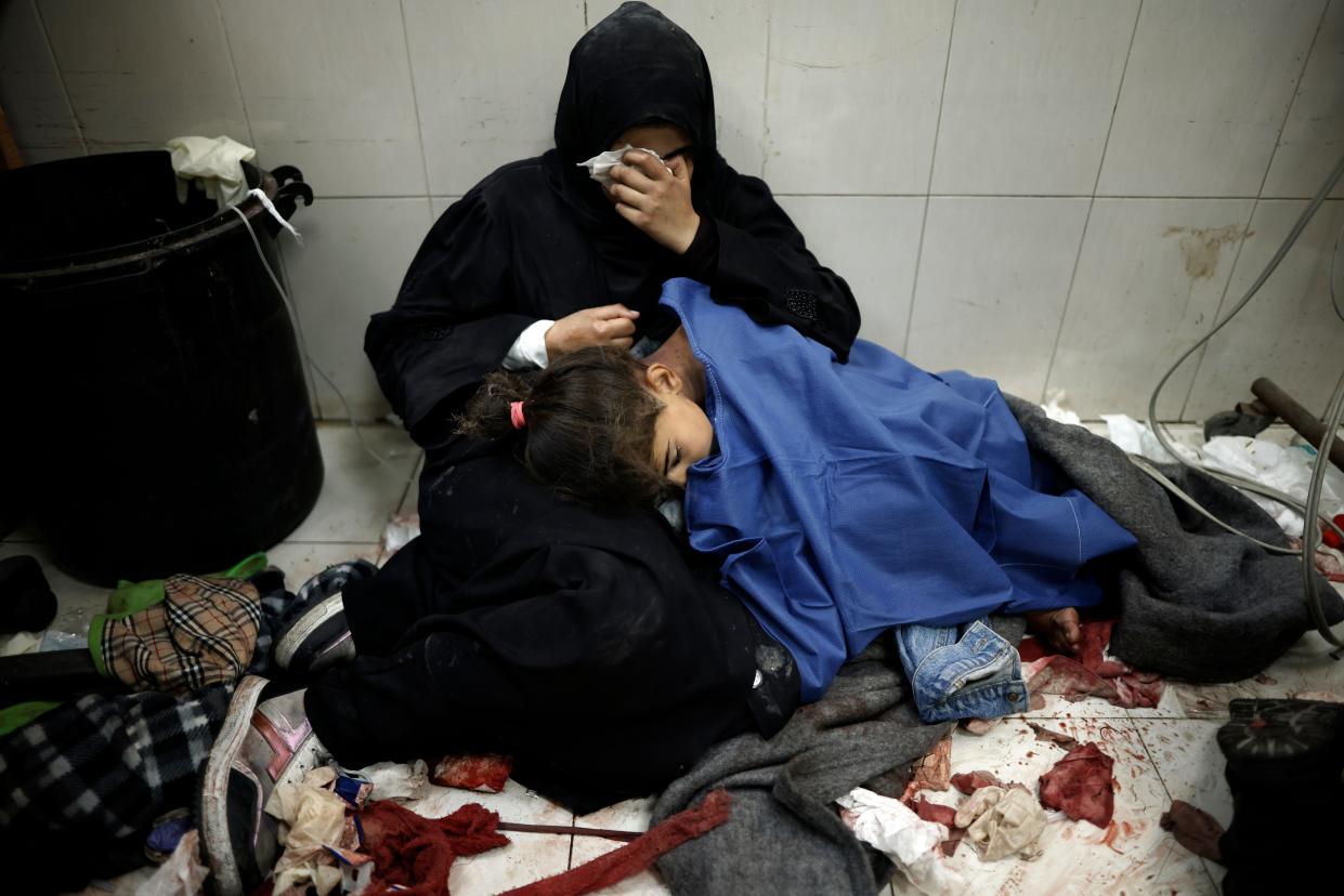 A Palestinian woman cries over a young bombing victim receiving treatment at the Nasser Hospital in the southern Gaza Strip on Jan. 22, 2024.