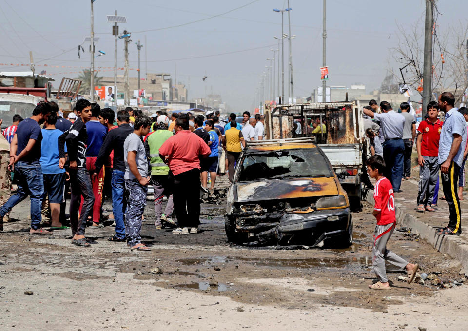 Civilians inspect the site of a car bomb attack in Baghdad's Sadr City neighborhood, Iraq, Wednesday, April 9, 2014. Iraqi officials say a series of car bombs has hit several mostly Shiite neighborhoods in Baghdad, killed and wounded scores of people, according to Iraqi officials. (AP Photo/Karim Kadim)