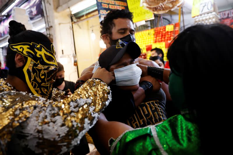 Lucha libre fighters encourage maskless Mexicans to wear masks at the Central Abastos market, in Mexico City