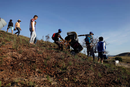 People walk with their belongings through a field, as they try to cross the border between Venezuela and Brazil in Pacaraima, Roraima state, Brazil February 23, 2019. REUTERS/Ricardo Moraes