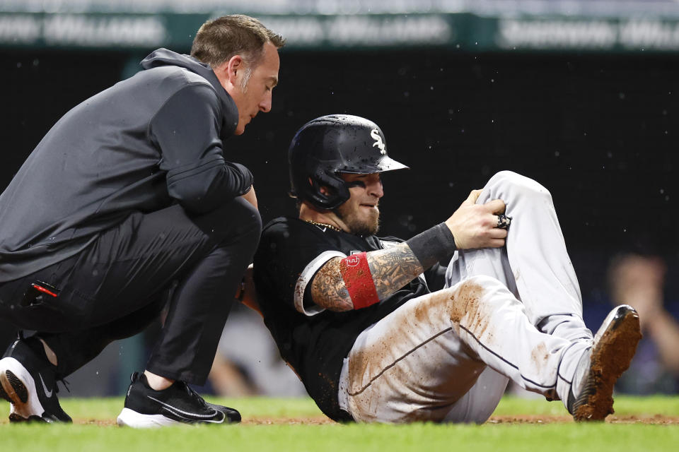 Chicago White Sox's Yasmani Granda, right,l is looked at by a trainer after being injured on a play at the plate during the seventh inning of a baseball game against the Cleveland Guardians, Saturday, Aug. 20, 2022, in Cleveland. (AP Photo/Ron Schwane)