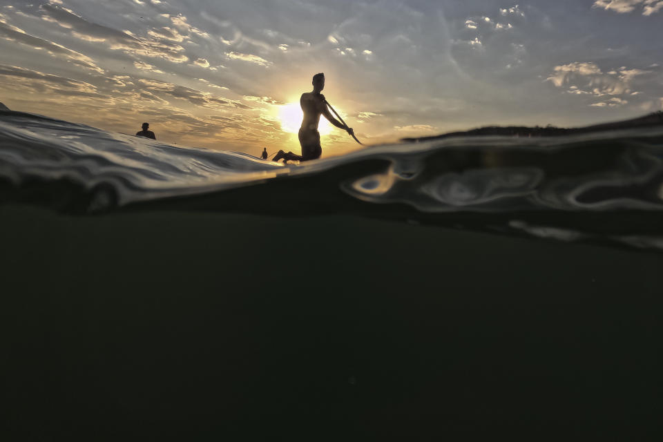 Un hombre flota sobre una tabla de paddle surf ante la playa de Copacabana, en Río de Janeiro, Brasil, al amanecer del 24 de agosto de 2023. Brasil sufre una ola de calor en pleno invierno en el hemisferio sur. (AP Foto/Bruna Prado)