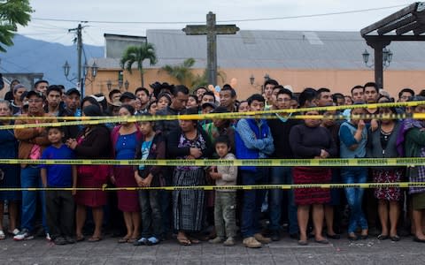 Neighbours stand outside a temporary morgue near the volcano in Alotenango - Credit: Luis Soto/ AP