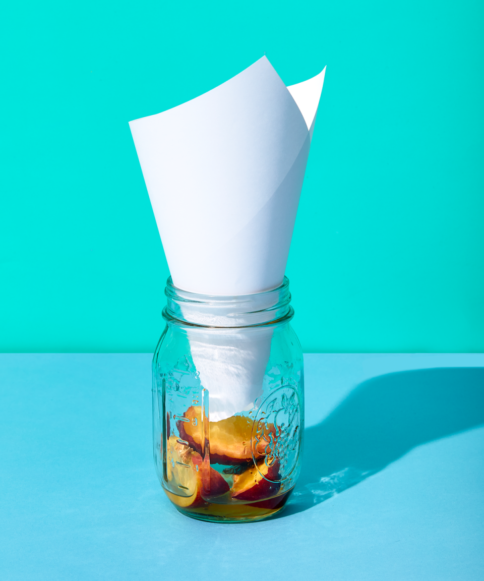 how to kill fruit flies, mason jar with cone shaped paper inside and rotting fruit at the bottom