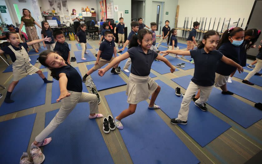 Los Angeles, CA - September 14: Accelerated Charter Elementary School on Wednesday, Sept. 14, 2022 in Los Angeles, CA. 2nd grade students Sophia Galarza, Jasmine Saloj and Giselle Calderon stretch to instructions from Yoga instructor Sacha Taylor and Leah Gallegos, a co-founder of People's Yoga as they lead students at Accelerated Charter Elementary School in Los Angeles in a half hour yoga session. People's Yoga, which may be the only yoga studio in East L.A. was created to offer accessible yoga classes in that geography. (Al Seib / For The Times)