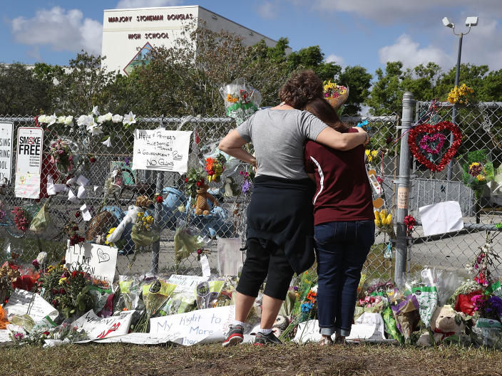 <p>Margarita Lasalle (R), the budget keeper, and Joellen Berman, Guidance Data Specialist, look on at the memorial in front of Marjory Stoneman Douglas High School as teachers and staff are allowed to return to the school for the first time since the mass shooting on campus on February 23, 2018 in Parkland, Fla. (Photo: Joe Raedle/Getty Images) </p>