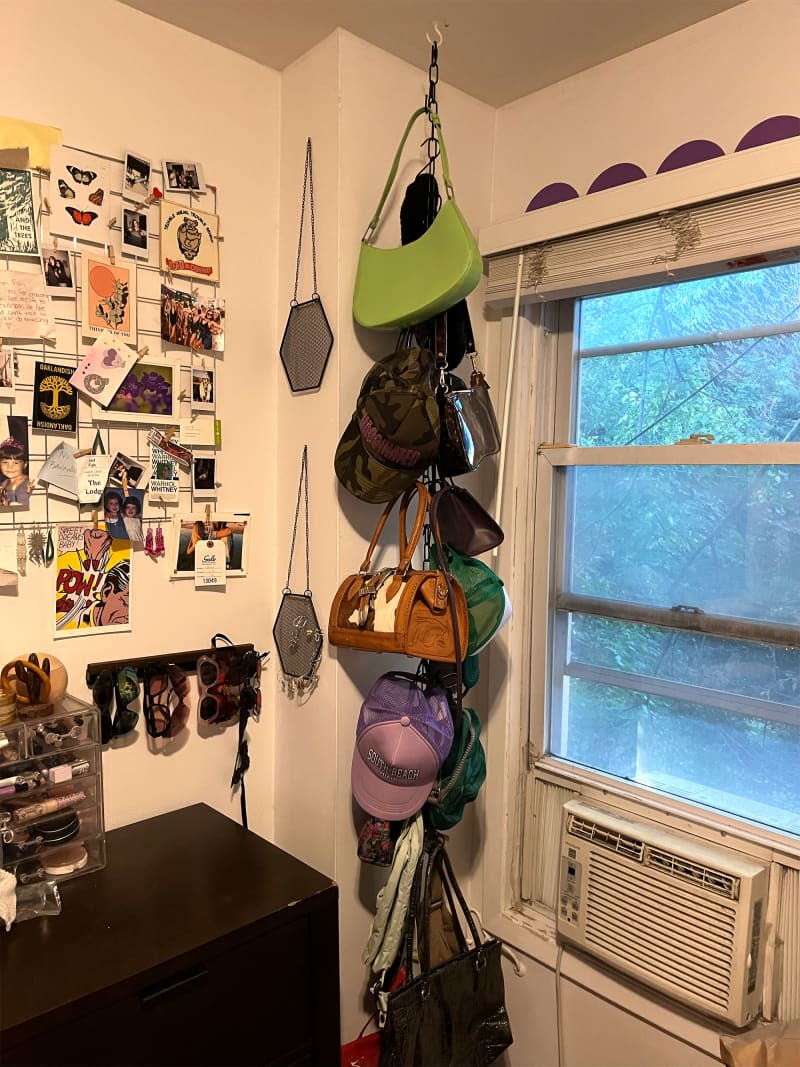 Purses hanging in corner of bedroom.