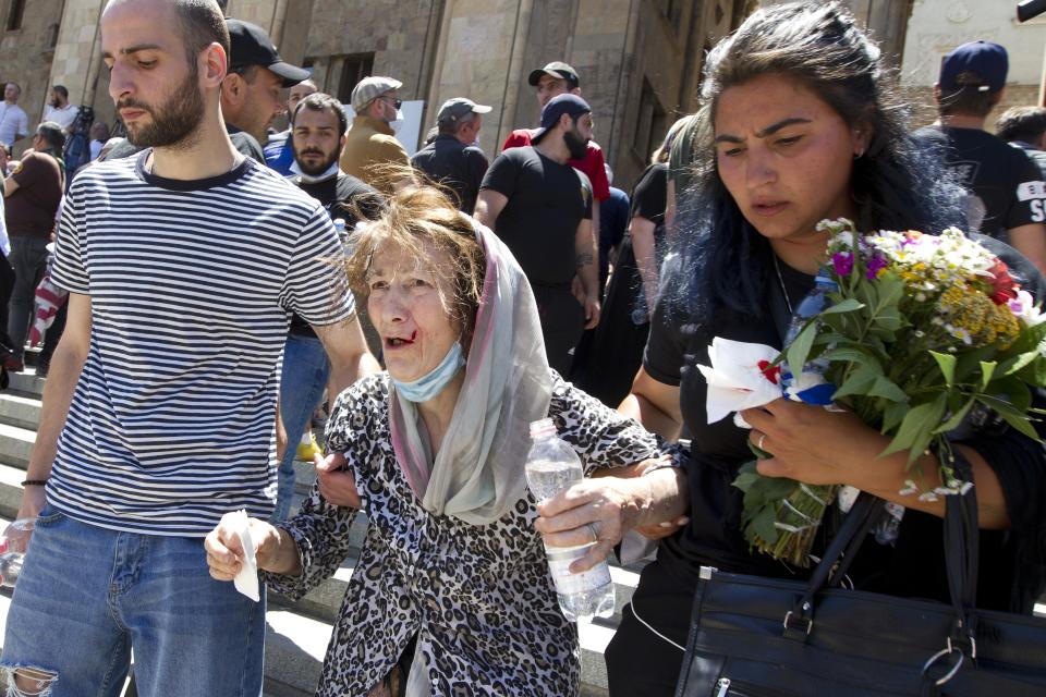 People help a wounded elderly opponent of the march while they block off the capital's main avenue to an LGBT march in Tbilisi, Georgia, Monday, July 5, 2021. A protest against a planned LGBT march in the Georgian capital turned violent on Monday as demonstrators attacked journalists. Organizers of the Tbilisi March For Dignity that was to take place in the evening cancelled the event, saying authorities had not provided adequate security guarantees. (AP Photo/Shakh Aivazov)