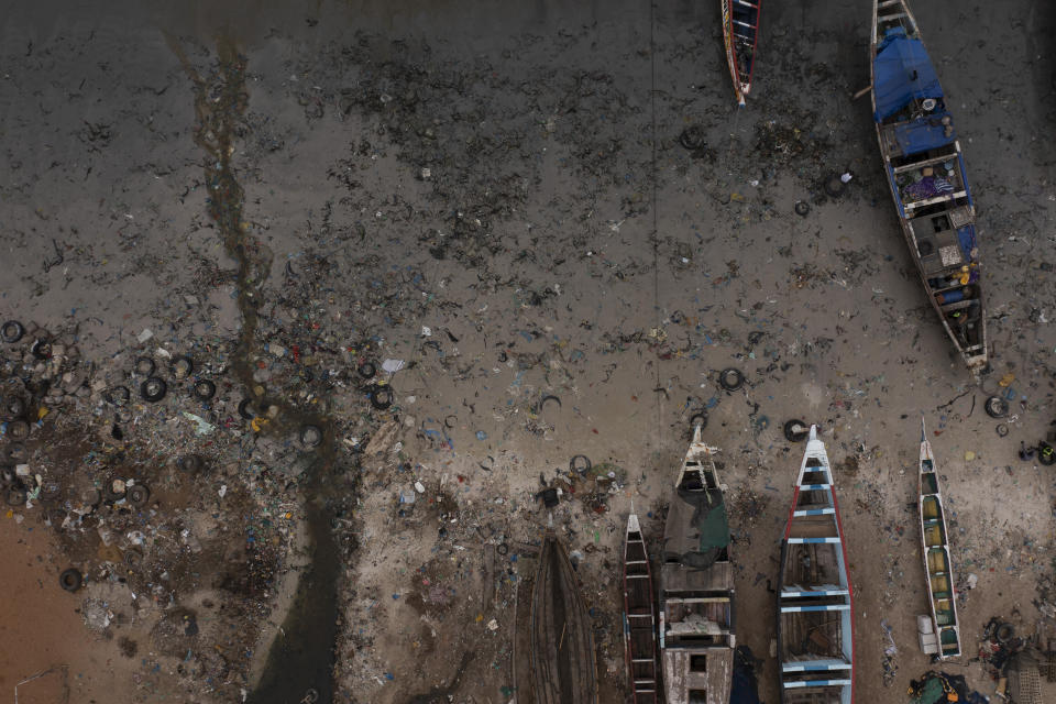 Open sewage flows to the ocean next to traditional boats known as pirogues at the Yarakh Beach in Dakar, Senegal, Tuesday, Nov. 8, 2022. In 2020, Senegal passed a law that banned some plastic products. But if the mountains of plastic garbage on this beach are any indication, the country is struggling with enforcement. (AP Photo/Leo Correa)