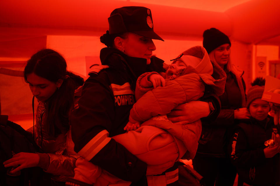 FILE - A firefighter holds the child of a refugee fleeing the war from neighboring Ukraine as they wait to be processed by border police after crossing the border by ferry at the Isaccea-Orlivka border crossing, in Romania, Friday, March 25, 2022. Since Russia launched its attacks against Ukraine on Feb. 24, more than 6 million people have fled war-torn Ukraine, the United Nations refugee agency announced Thursday, May 12, 2022. (AP Photo/Andreea Alexandru, File)
