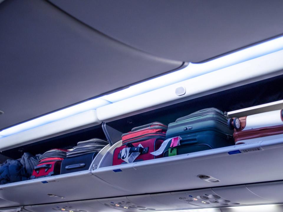 Carry-on bags in an overhead compartment.