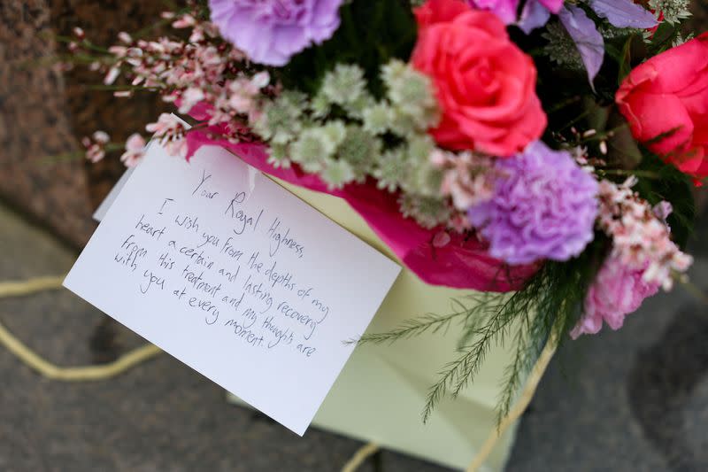 Un mensaje para la princesa Catalina junto a un ramo de flores cerca del castillo de Windsor, Reino Unido.