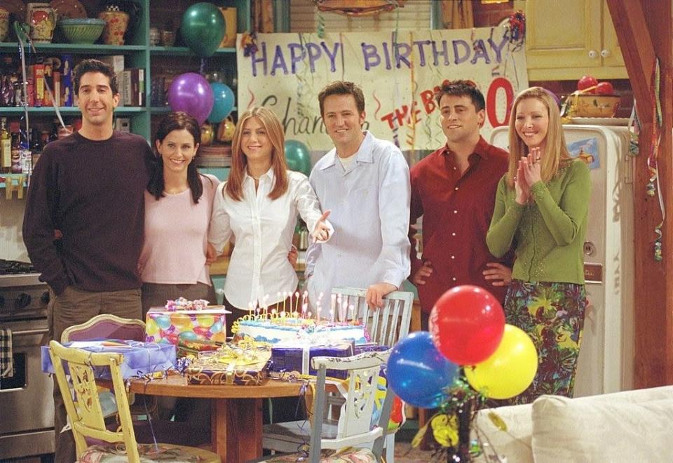 the cast celebrating a birthday in monica's kitchen
