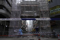 Government workers wearing personal protective equipment stand guard at the closed area in Jordan district, in Hong Kong, Sunday, Jan. 24, 2021. Thousands of Hong Kong residents were locked down Saturday in an unprecedented move to contain a worsening outbreak in the city, authorities said. (AP Photo/Vincent Yu)