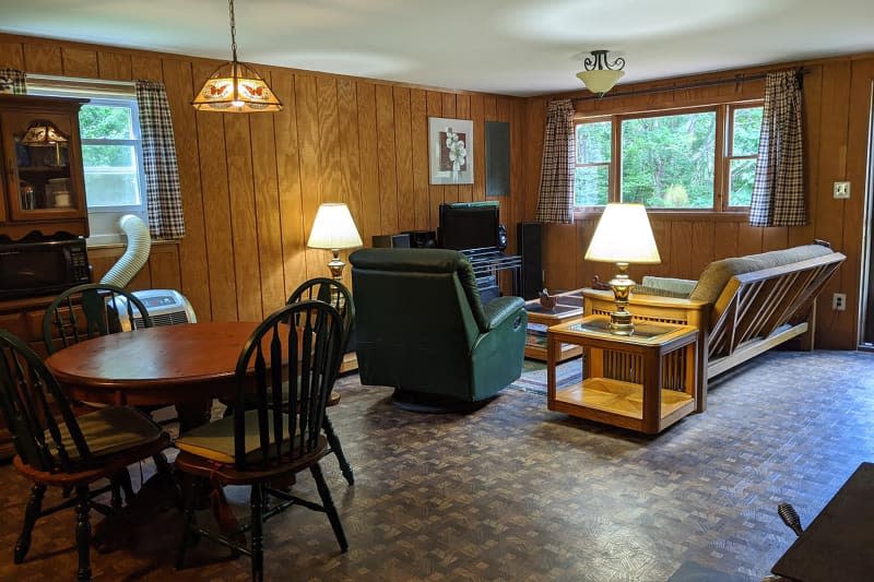 Dark wood panels in living and dining space of cabin before renovation.