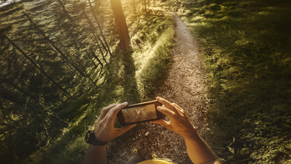 POV Trail running in the forest: checking map on mobile