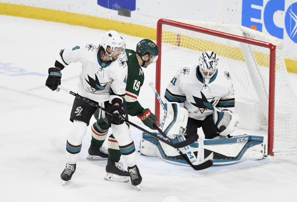 San Jose Sharks' goalie Martin Jones, right, makes a glove save on a shot by Minnesota Wild's Jason Zucker (16) behind the Sharks' Brenden Dillon in the third period of an NHL hockey game, Saturday, Feb. 15, 2020, in St. Paul, Minn. San Jose won 2-0.(AP Photo/Tom Olmscheid)