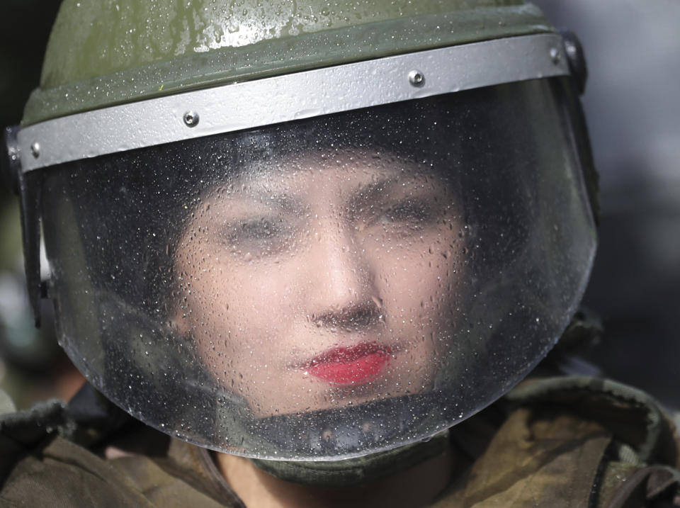 In this Oct. 26, 2019 photo, a female police officer stands in the street during an anti-government protest in Santiago, Chile. Chile has been facing days of unrest, triggered by a relatively minor increase in subway fares. The protests have shaken a nation noted for economic stability over the past decades, which has seen steadily declining poverty despite persistent high rates of inequality. (AP Photo/Rodrigo Abd)