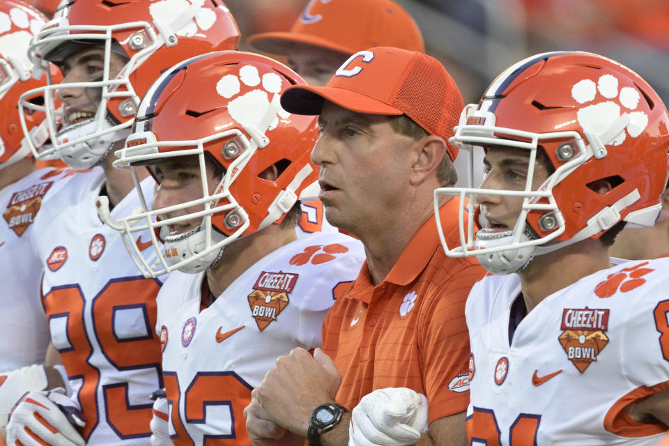 FILE - Clemson head coach Dabo Swinney, second from right, walks with players on the field before the Cheez-It Bowl NCAA college football game against Iowa State, Wednesday, Dec. 29, 2021, in Orlando, Fla. The perpetually positive Swinney probably has more need for it these days with his team breaking in three new assistants including first-time Clemson coordinators on defense in Wes Goodwin and offense in Brandon Streeter. (AP Photo/Phelan M. Ebenhack, File)