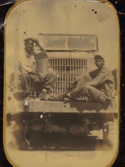Technical Sergeant Robert William Venable, Jr.,(right) seated on a truck bumper.