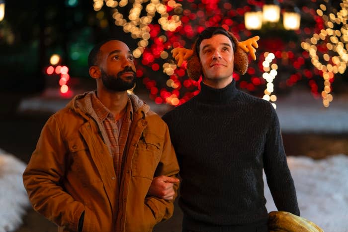 Michael Urie wearing reindeer ears as he stands arm-in-arm with Philemon Chambers in a scene from Single All the Way