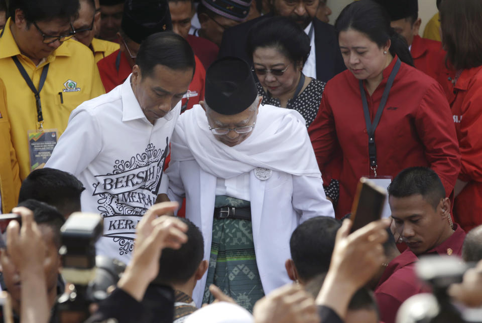 Indonesian President Joko "Jokowi" Widodo, center left, and his running mate Ma'ruf Amin, center right, walk together prior to formal registration as candidates for the 2019 presidential election in Jakarta, Indonesia. Friday, Aug. 10,2018. The battle lines for Indonesia's 2019 presidential election were drawn Friday as president Jokowi formally registered as a candidate after choosing a conservative Islamic cleric as his running mate. (AP Photo/Tatan Syuflana)