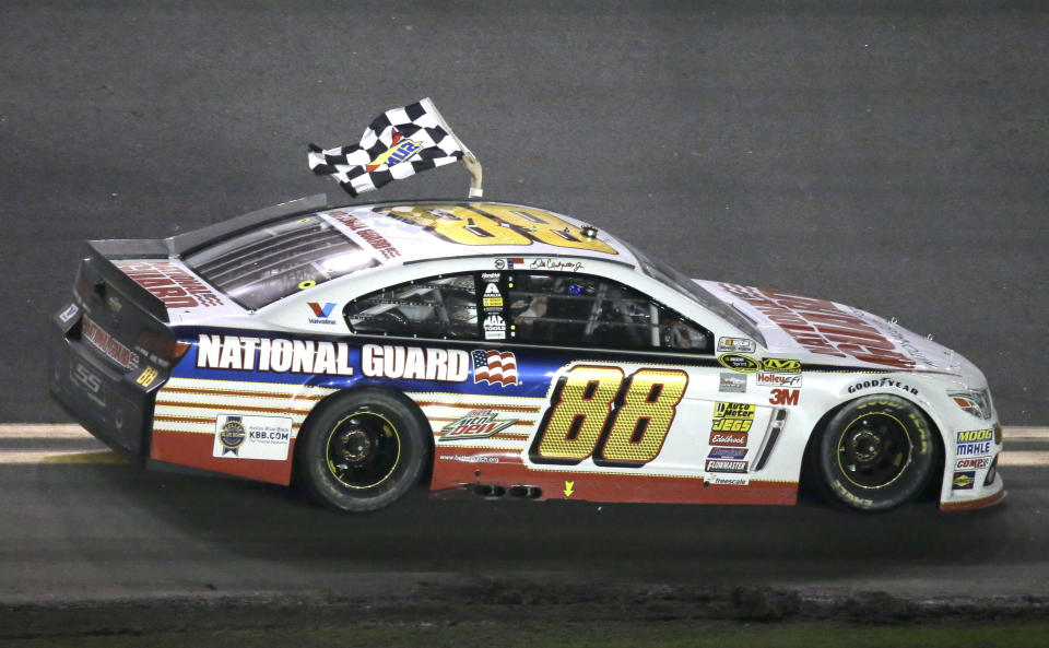 Dale Earnhardt Jr. drives in front of fans in the grandstands waving the checkered flag after winning the Daytona 500 NASCAR Sprint Cup Series auto race at Daytona International Speedway in Daytona Beach, Fla., Sunday, Feb. 23, 2014. (AP Photo/John Raoux)