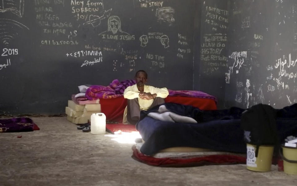 In this Wednesday, July 17, 2019 frame grab from video, a migrant rests in a detention center in the city of Sabha, which is about 650 kilometers, or 400 miles, south of the capital, Tripoli, Libya. Migrants held at a small, dilapidated detention center in the southern Libyan city of Sabha say they are being neglected by international organizations and often go hungry due to lack of food. (AP Photo)