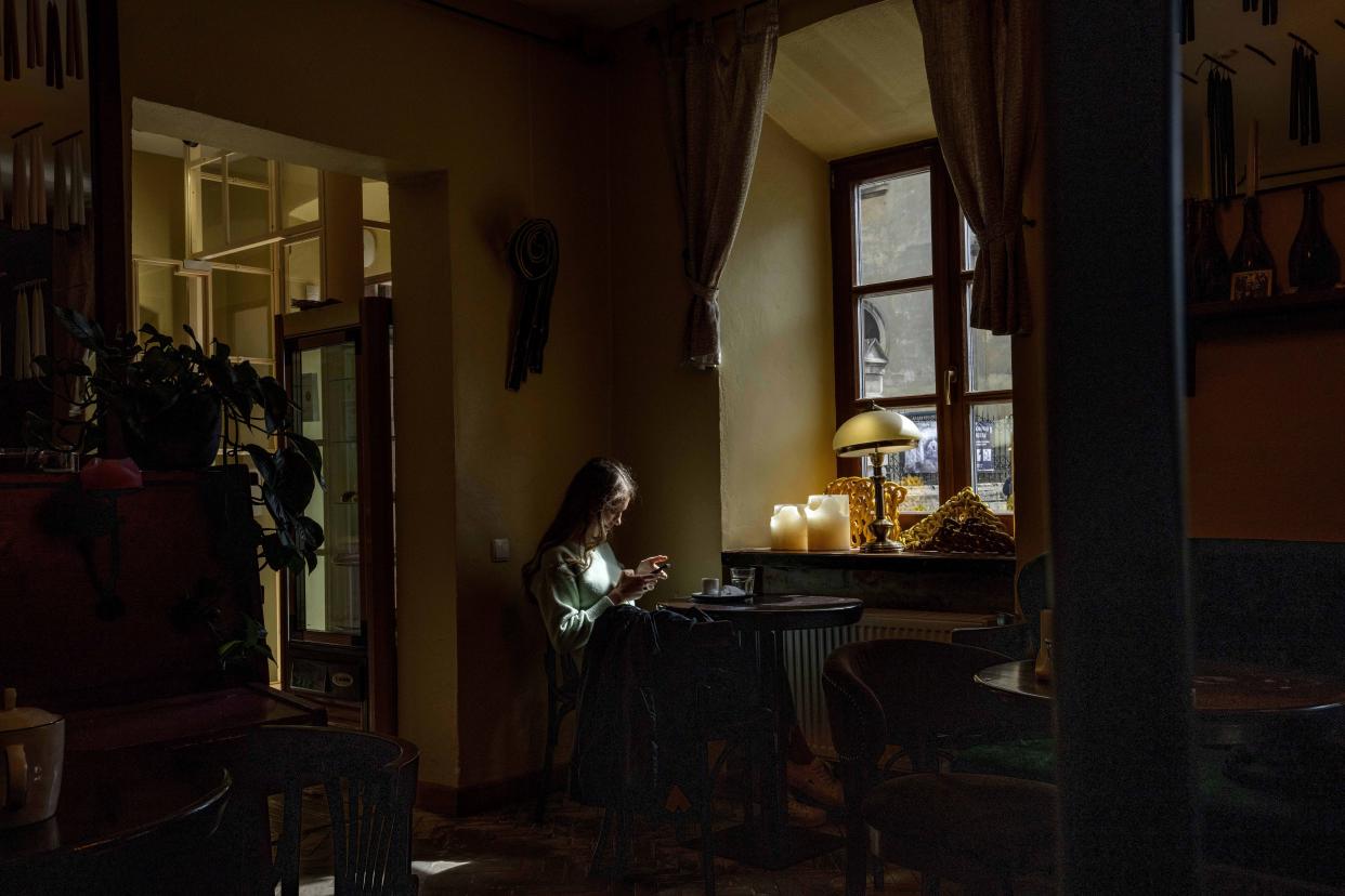 A woman sits at a coffee shop a day after Russian rockets hit an oil facility and factory in an industrial area, in Lviv, western Ukraine, Sunday, March 27, 2022. (AP Photo/Nariman El-Mofty)