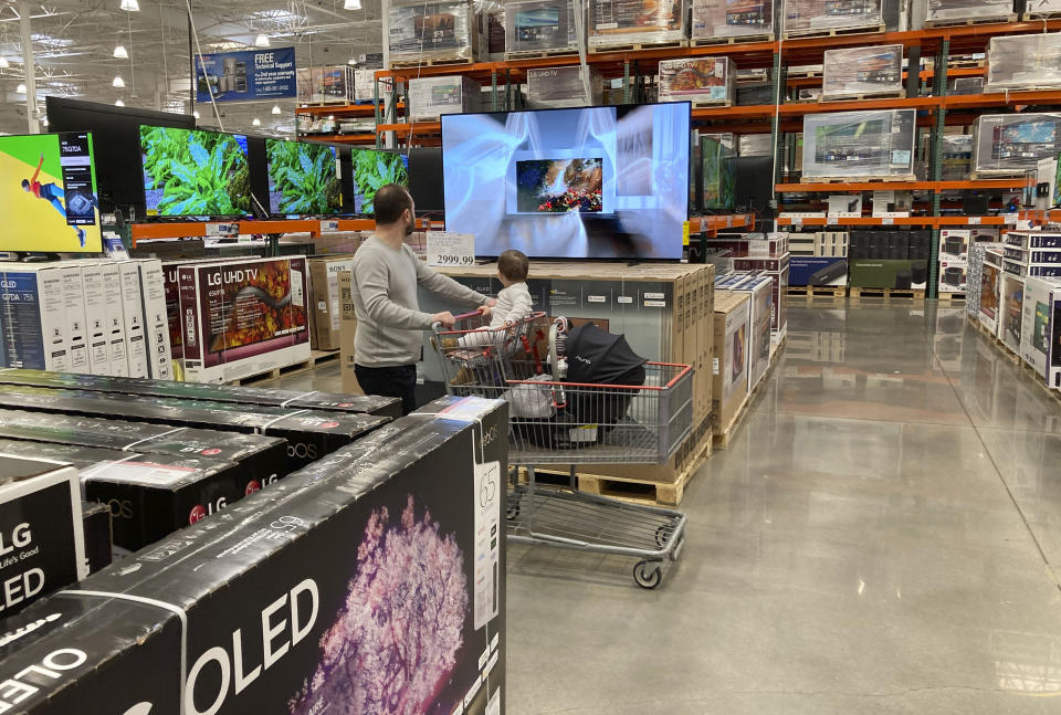A shopper pushes a child in a cart while browsing big-screen televisions on display in the electronics section of a Costco warehouse, Tuesday, March 29, 2022, in Lone Tree, Colo. U.S consumers have so far defied higher prices for gas, food, and rent and have been spending more in 2022, providing crucial support to the economy. How long that can continue will be one of the key factors affecting the economy and inflation this year. (AP Photo/David Zalubowski)