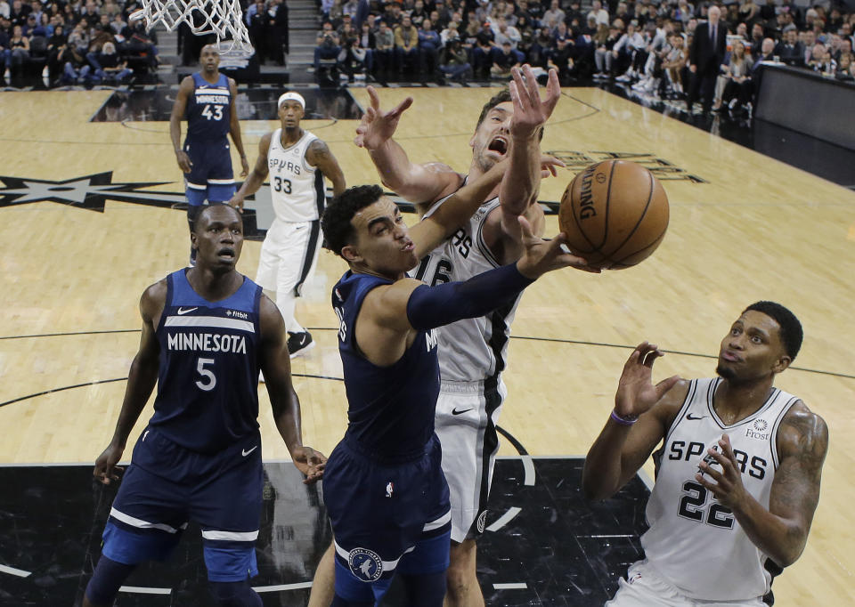 Minnesota Timberwolves guard Tyus Jones (1) tires to score past San Antonio Spurs center Pau Gasol (16) and forward Rudy Gay, right, during the first half of an NBA basketball game, Wednesday, Oct. 17, 2018, in San Antonio. (AP Photo/Eric Gay)