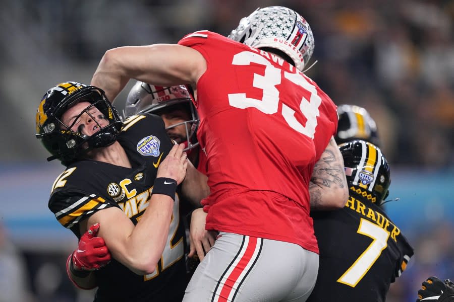 ARLINGTON, TEXAS – DECEMBER 29: Brady Cook #12 of the Missouri Tigers is hit by JT Tuimoloau #44 and Jack Sawyer #33 of the Ohio State Buckeyes during the first quarter in the Goodyear Cotton Bowl at AT&T Stadium on December 29, 2023 in Arlington, Texas. (Photo by Sam Hodde/Getty Images)