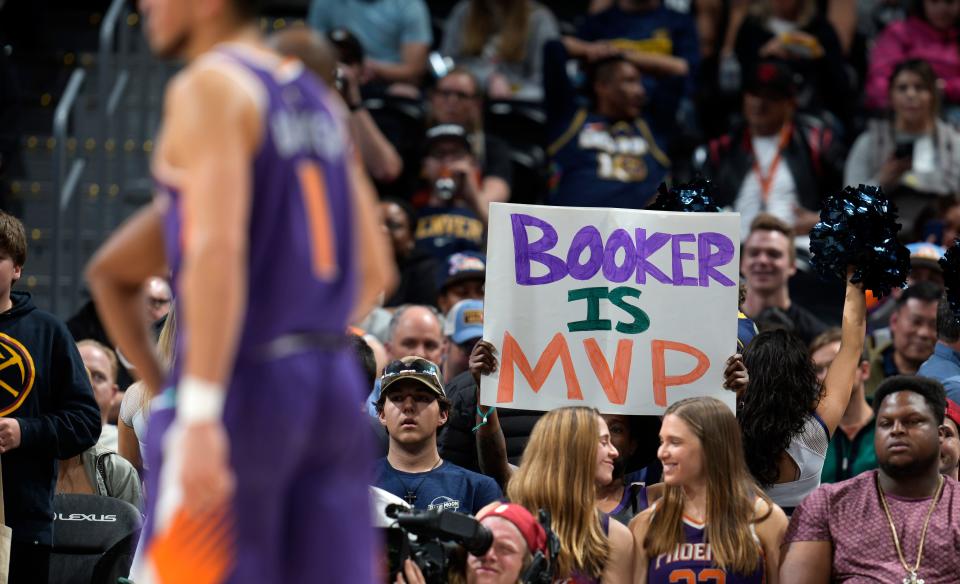 A fan holds up a sign in support of Phoenix Suns guard Devin Booker, front, late in the second half of the Suns' NBA basketball game against the Denver Nuggets on Thursday, March 24, 2022, in Denver.