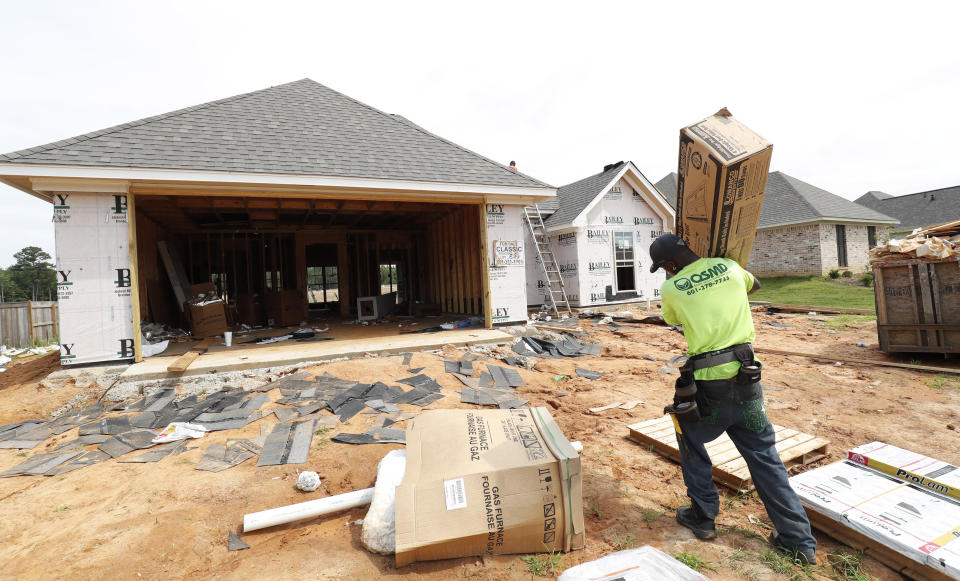 In this June 19, 2019, photo a worker carries supplies for a new house in a Brandon, Miss., neighborhood. On Tuesday, June 25, The Commerce Department reports on sales of new homes in May. (AP Photo/Rogelio V. Solis)