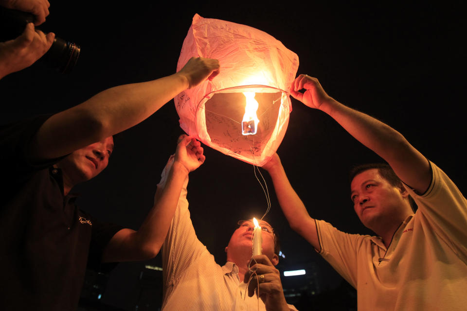 People prepare to release a sky lantern during a candlelight vigil for passengers aboard a missing Malaysia Airlines plane in Kuala Lumpur, Malaysia, Monday, March 10, 2014. The search operation for the missing Malaysia Airlines Flight MH370 which has involved 34 aircraft and 40 ships from several countries covering a 50-nautical mile radius from the point the plane vanished from radar screens between Malaysia and Vietnam continues after its disappearance since Saturday. (AP Photo/Lai Seng Sin)