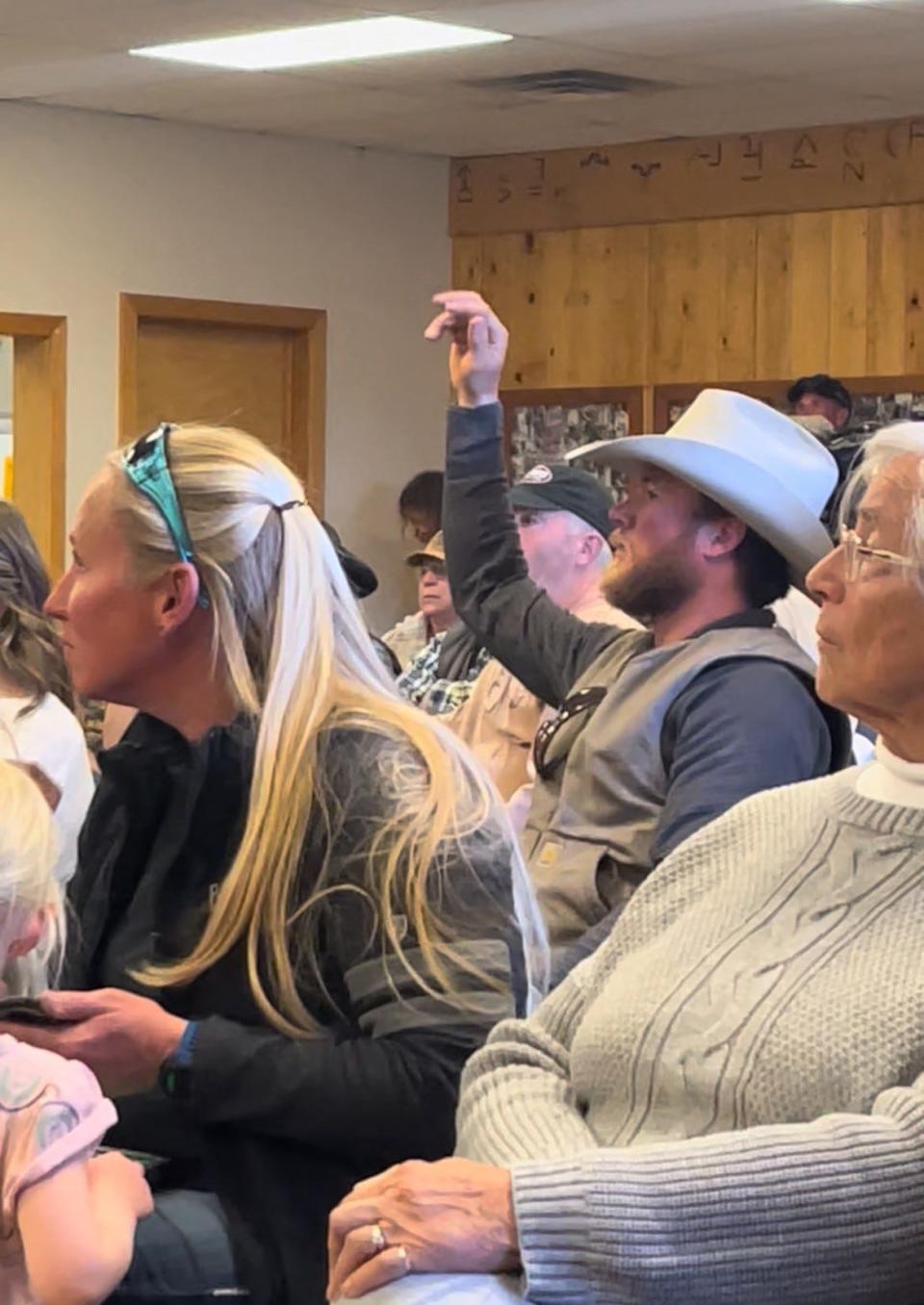 A rancher raises his hand to ask a question during a Colorado Parks and Wildlife meeting to discuss wolves in Kremmling, Colo., on Tuesday, April 9, 2024.