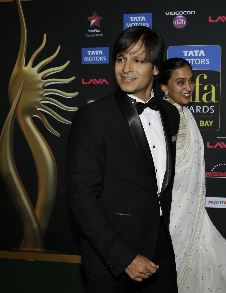 Indian film star Vivek Oberoi walks with his wife Priyanka Alva Oberoi on the green carpet as they arrive for 15th annual International Indian Film Awards Saturday, April 26, 2014, in Tampa, Fla. (AP Photo/Chris O'Meara)