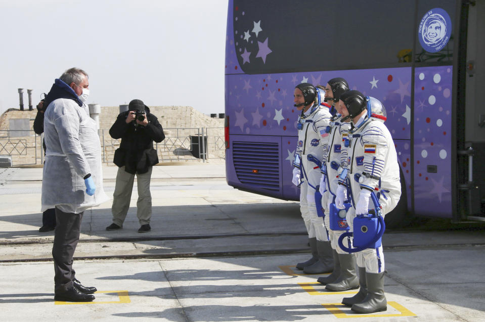 In this handout photo released by Roscosmos Space Agency Press Service U.S. astronaut Chris Cassidy, left, Russian cosmonauts Anatoly Ivanishin, centre, and Ivan Vagner, members of the main crew of the expedition to the International Space Station (ISS), report to head or Russian space agency Dmitry Rogozin prior the launch of Soyuz MS-16 space ship at the Russian leased Baikonur cosmodrome, Kazakhstan, Thursday, April 9, 2020. (Roscosmos Space Agency Press Service via AP)
