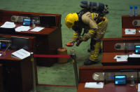 Firefighters inspect the main chamber of the Legislative Council after a pro-democracy lawmaker dropping a pot of a pungent liquid in the chamber in Hong Kong, Thursday, June 4, 2020. A Hong Kong legislative debate was suspended Thursday afternoon ahead of an expected vote on a contentious national anthem bill after pro-democracy lawmakers staged a protest. (AP Photo/Vincent Yu)