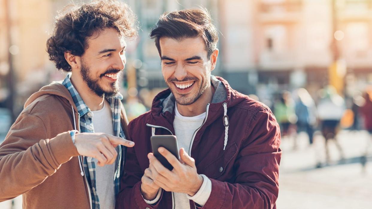 two men laughing and looking at phones