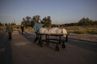 Member of Hevra Kadisha, an organization which prepares bodies of deceased Jews for burial according to Jewish tradition, pushes a body during a funeral of a Jewish man who died from coronavirus in the costal city of Ashkelon, Israel, Thursday, April 2, 2020. (AP Photo/Tsafrir Abayov)