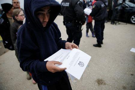 A boy reads an announcement distributed by Greek police officers informing refugees and migrants that the borders to Macedonia are closed and they should consider moving to relocation centers, at a makeshift camp at the Greek-Macedonian border near the village of Idomeni, Greece, March 18, 2016. REUTERS/Alkis Konstantinidis