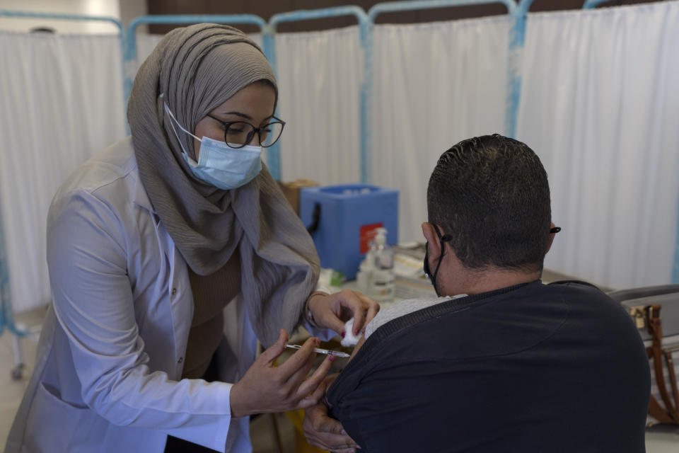 A health care worker administers a dose of the Pfizer coronavirus vaccine in a COVID-19 vaccinating center, in the West Bank city of Ramallah, Thursday, Feb. 3, 2022. Palestinians are facing a winter coronavirus surge driven by the omicron variant, placing stress on the medical system even though vaccines are widely available. (AP Photo/Nasser Nasser)