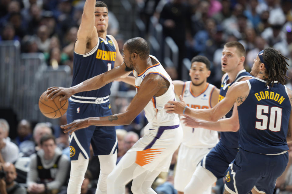 Phoenix Suns forward Kevin Durant, second from left, passes the ball while defended by, from left to right, Denver Nuggets forward Michael Porter Jr., center Nikola Jokic and forward Aaron Gordon in the first half of Game 2 of an NBA second-round playoff series Monday, May 1, 2023, in Denver. (AP Photo/David Zalubowski)