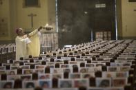 The Archbishop of Lima Carlos Castillo swings a censer over several of the more than 4 thousand portraits of COVID-19 victims during the Corpus Christi Mass at the Cathedral of Lima, Peru, Sunday, June 14, 2020. (AP Photo/Rodrigo Abd)