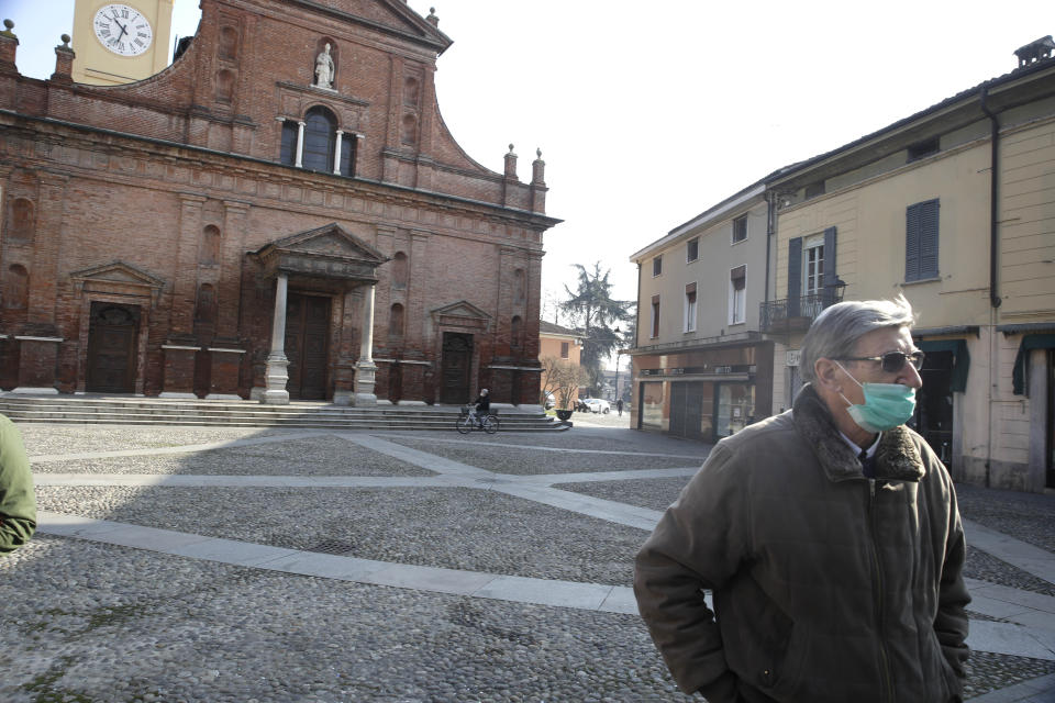 A man wearing a mask stands in front of the San Biagio church in Codogno, near Lodi, Northern Italy, Saturday, Feb. 22, 2020. A dozen towns in northern Italy are on effective lockdown after the new virus linked to China claimed a first fatality in Italy and sickened an increasing number of people. The secondary contagions have prompted local authorities in towns of Lombardy and Veneto to order schools, businesses, and restaurants closed, and to cancel sporting events and Masses. (AP Photo/Luca Bruno)