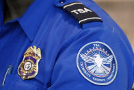 FILE - In this June 24, 2020, file photo, a Transportation Security Administration officer works at Love Field in Dallas. President Donald Trump has repeatedly credited his February ban on travelers from mainland China as his signature move against the advance of the coronavirus pandemic -- a “strong wall” that allowed only U.S. citizens inside, he boasted in May. But Trump’s wall was more like a sieve. Exempted were thousands of residents of the Chinese territories of Hong Kong and Macau. (AP Photo/Tony Gutierrez, File)