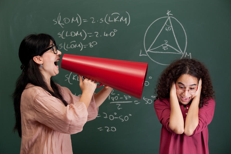 A teacher with a megaphone to a kid's ear