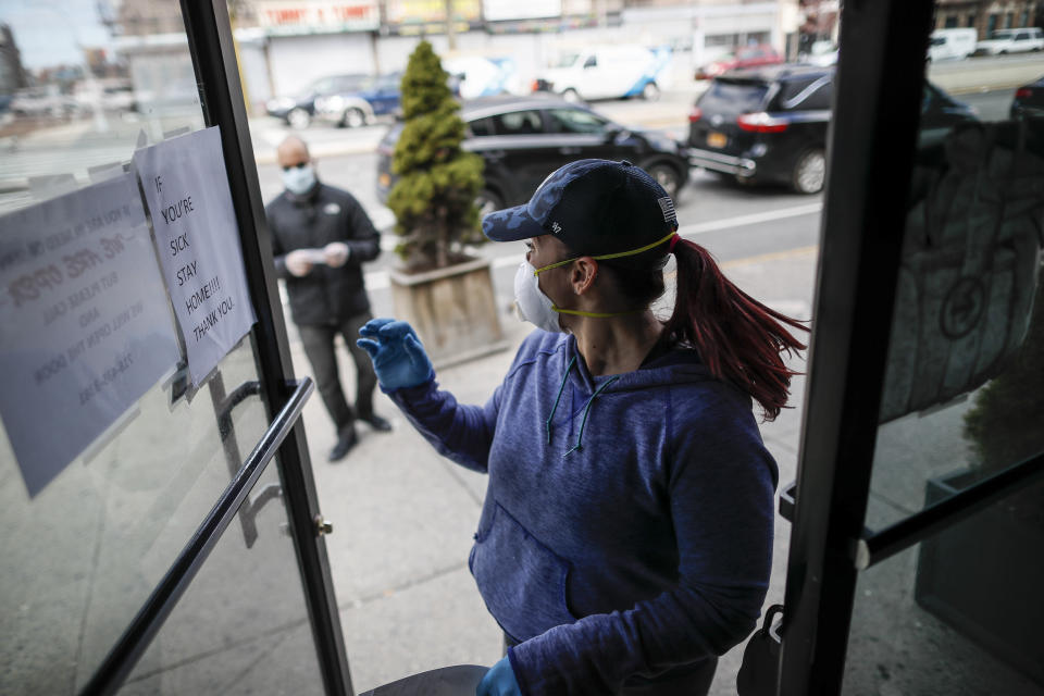 Employee Gina Hansen, right, enters her office to retrieve documentation for a client outside Daniel J. Schaefer Funeral Home Thursday, April 2, 2020, in the Brooklyn borough of New York. The company is equipped to handle 40-60 cases at a time. But amid the coronavirus pandemic, it was taking care of 185 Thursday morning. (AP Photo/John Minchillo)