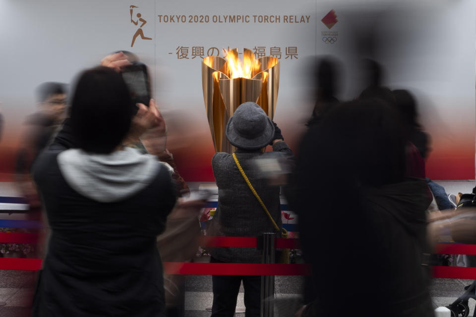 FILE - In this March 24, 2020, file photo, people take pictures of the Olympic Flame during a ceremony in Fukushima City, Japan. The Olympic flame has been removed from public display in Japan and it's not clear when it will reappear again or where. The flame arrived in Japan from Greece on March 26. (AP Photo/Jae C. Hong, File)